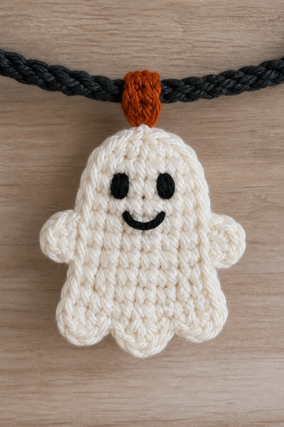 Close-up of an ivory ghost with embroidered face, scalloped hem, and orange spacer