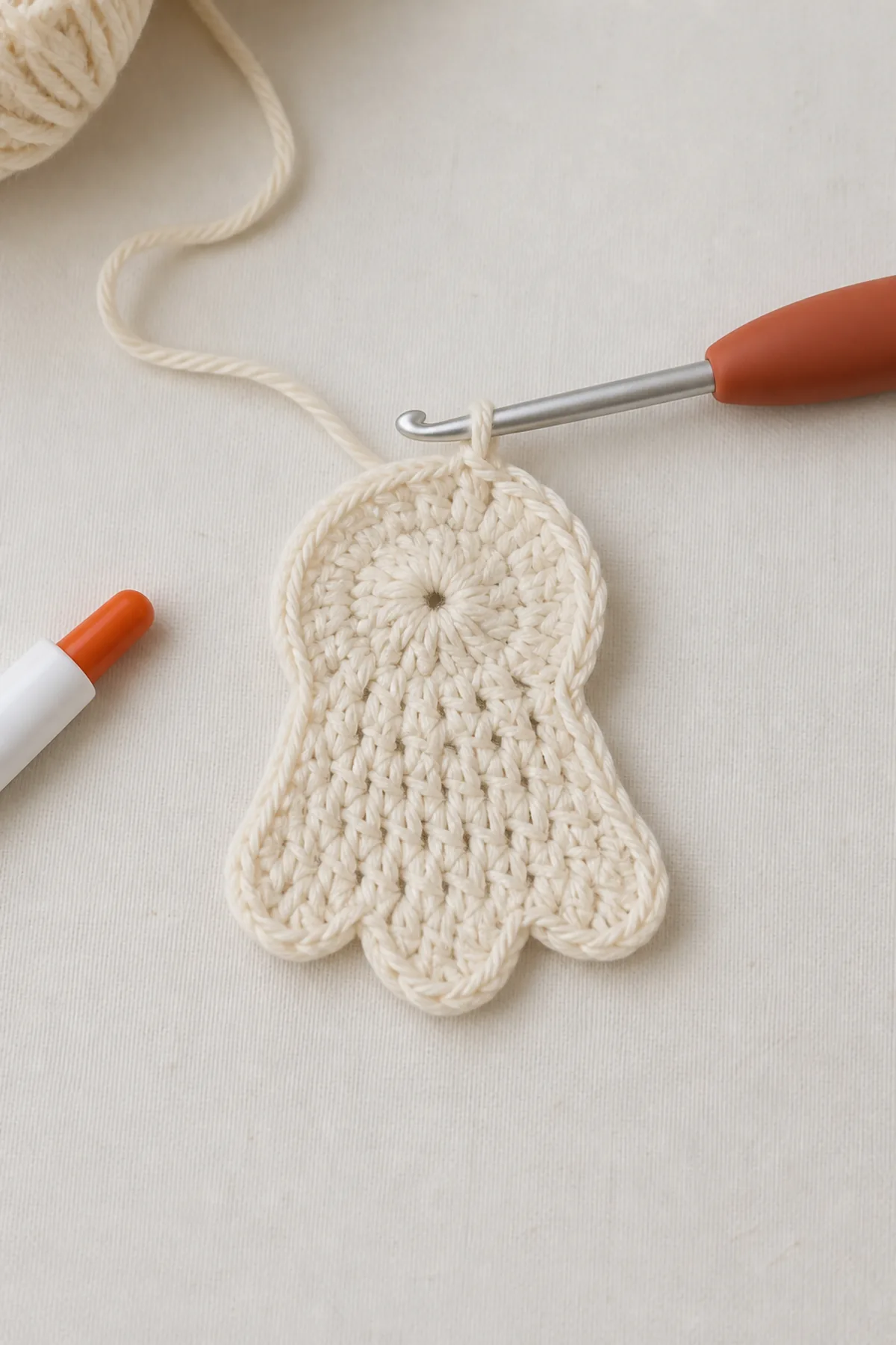 Small ivory crochet ghost motif being shaped in rows