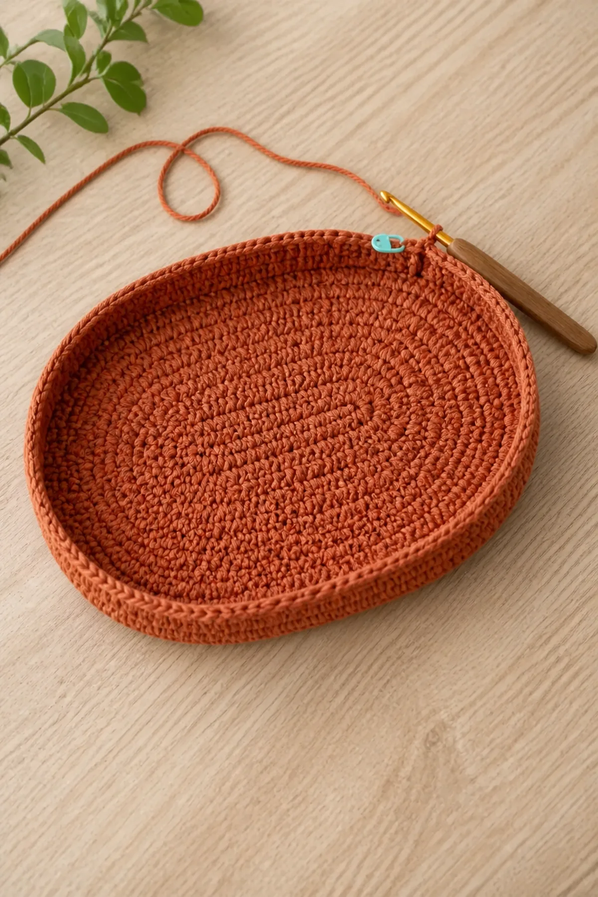 Terracotta oval crochet bag base with the first side rounds and active hook