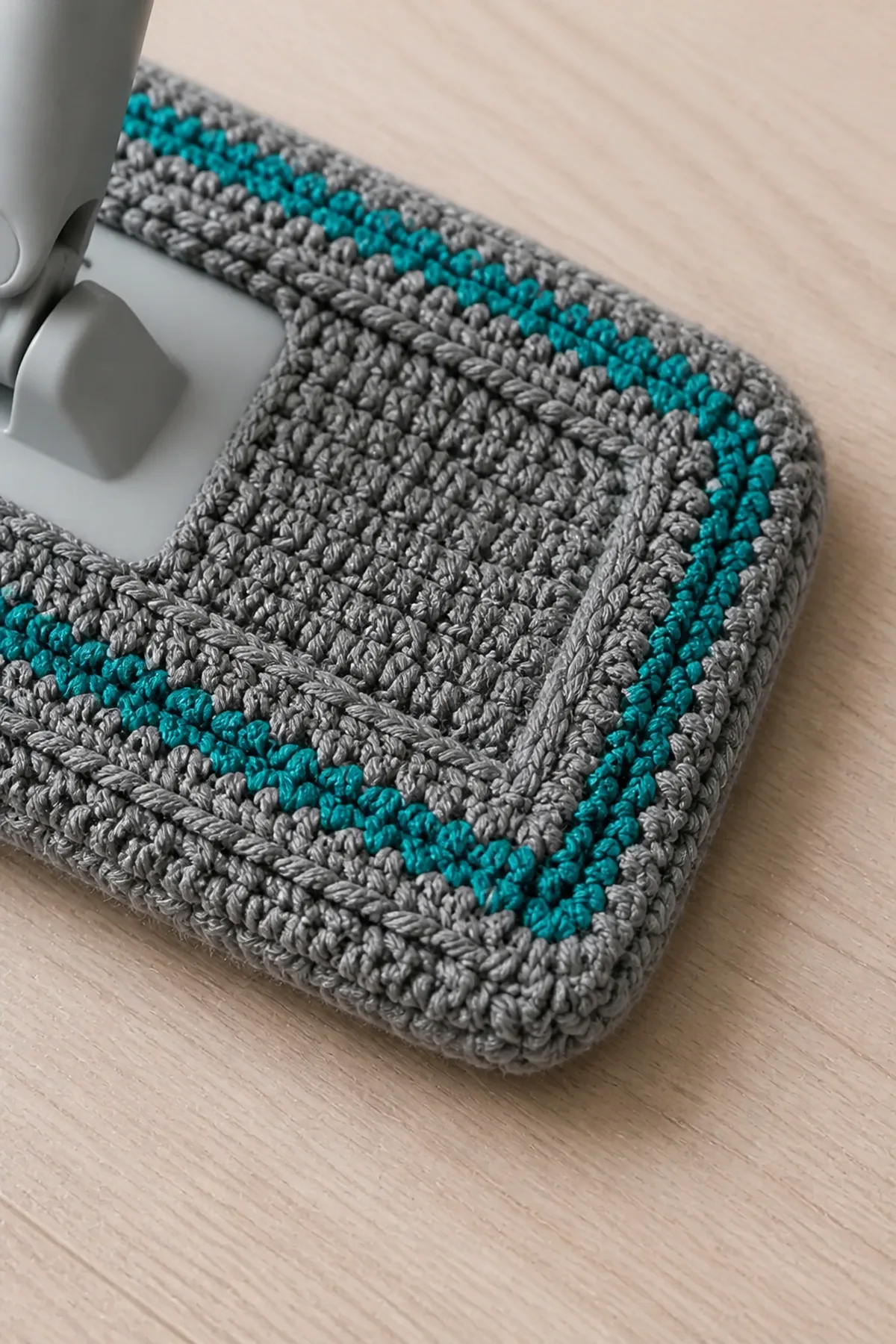 Close-up stitch detail on the gray reusable mop pad with teal stripes